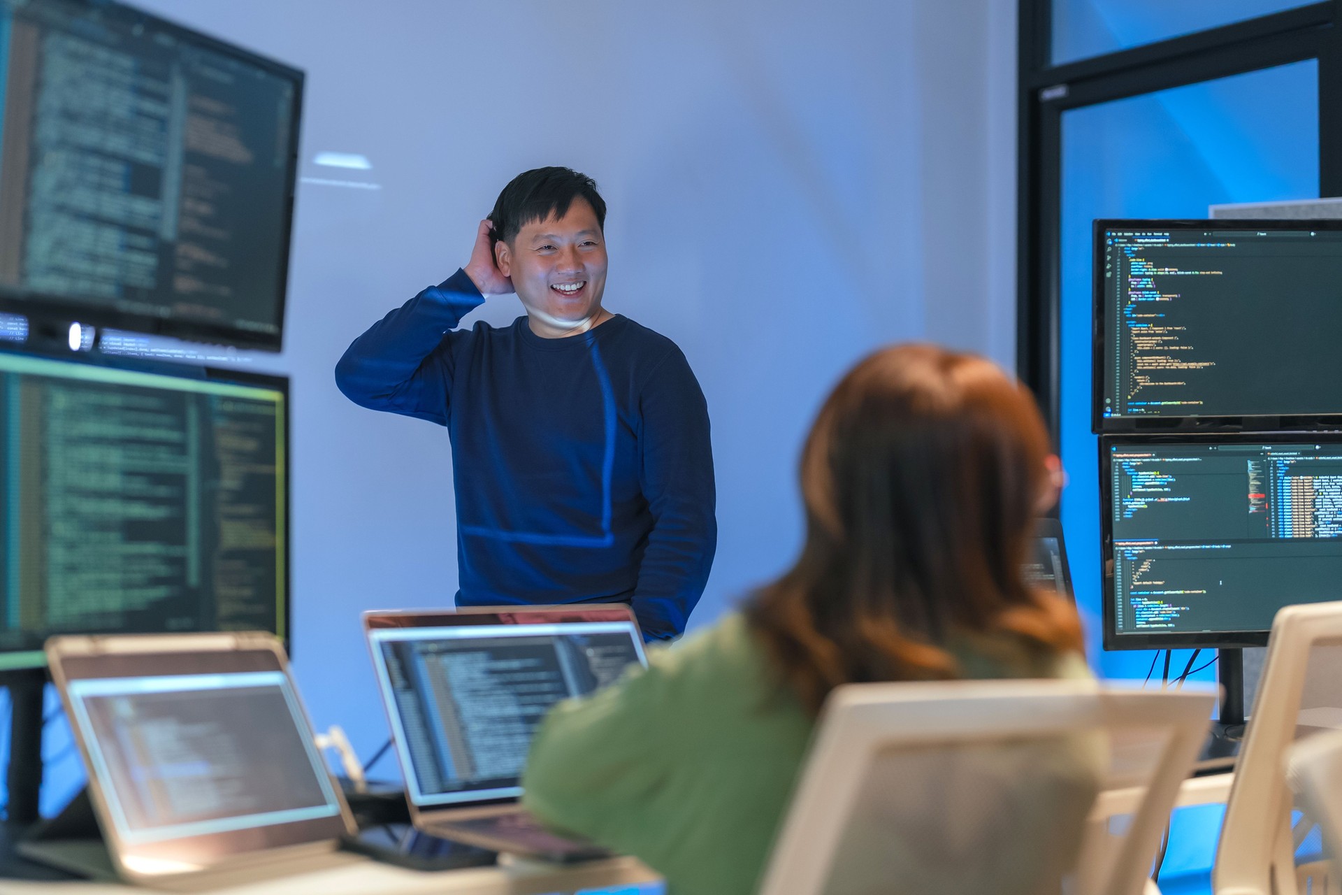 young Asian software development manager leads a late-night office discussion with his executive team, mentoring developers and analyzing source code to guide programming and project development